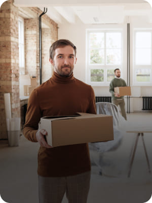 Homme portant un carton dans un bureau en cours de déménagement - Grospiron