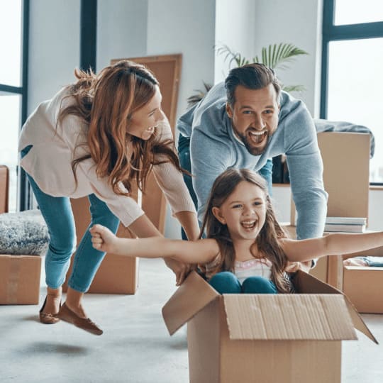 Famille jouant avec des cartons de déménagement, illustrant les bienfaits du service de déménagement en groupe de Grospiron