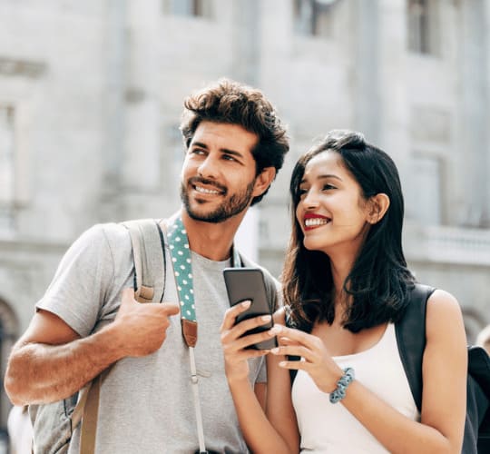 Couple souriant s’orientant en ville via smartphone, installation après déménagement avec Grospiron