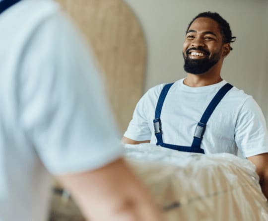 Déménageur souriant portant un meuble protégé, service national Grospiron