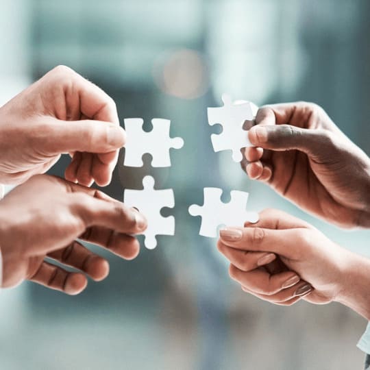 Mains assemblant un puzzle, illustrant le réseau international de partenaires logistiques de Grospiron