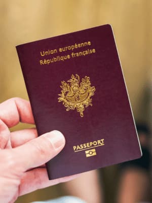 Passeport français tenu à la main, illustrant le service administratif de Grospiron pour les démarches internationales