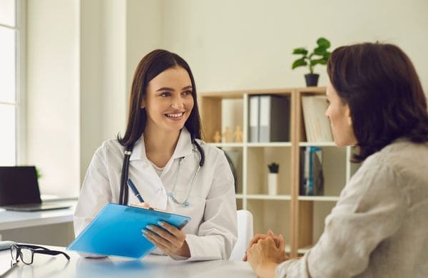 Médecin souriante en consultation avec une expatriée, assurance santé pour expatriés avec Grospiron